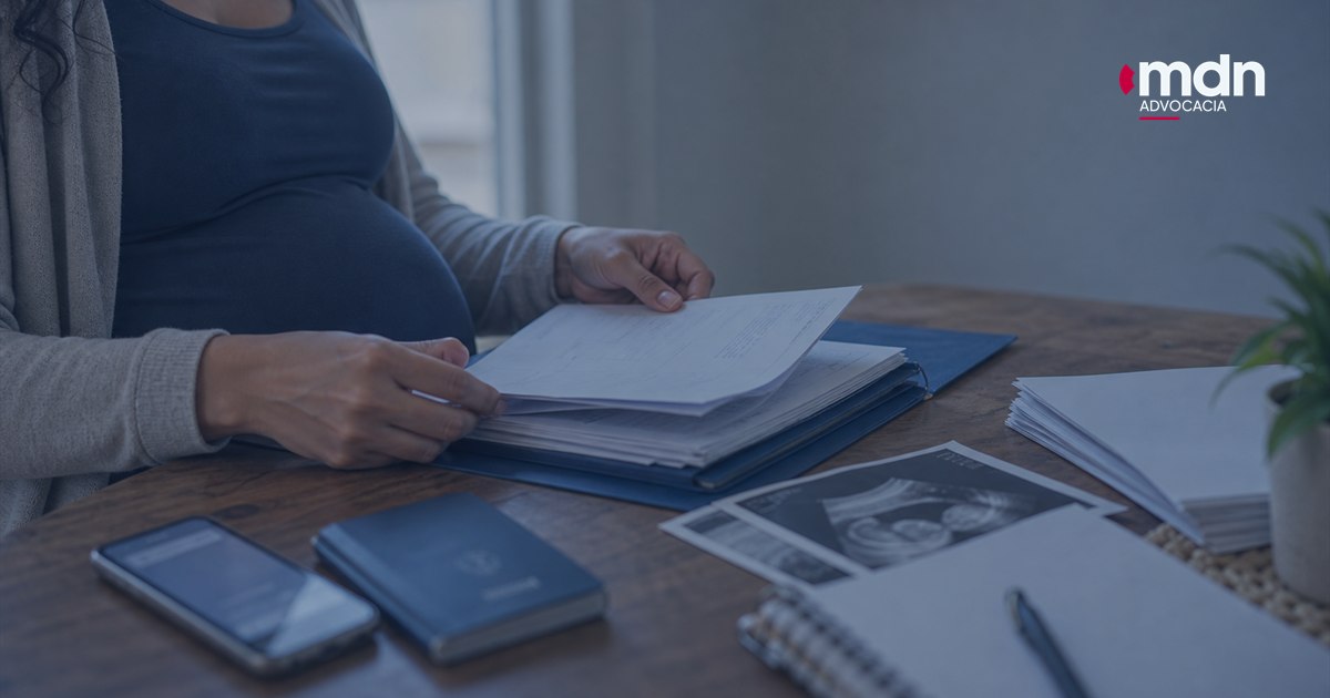 Documentos para processo por demissão de grávida organizados com ultrassom e carteira de trabalho sobre uma mesa.