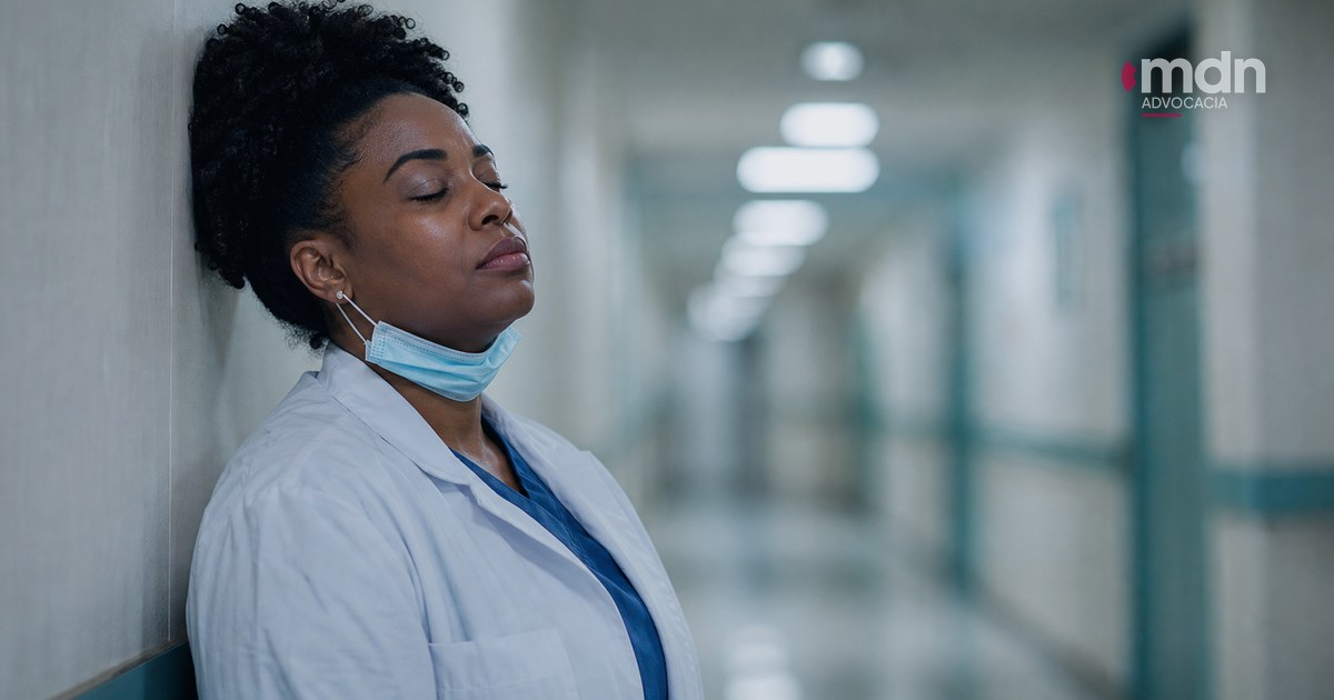 Profissional de enfermagem descansando em um corredor de hospital
